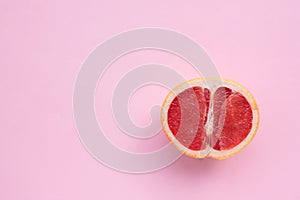 Grapefruit cut in half on a pink background. Close-up of citrus fruit on a colored backdrop. Top view. Copy space