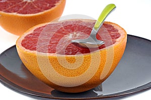 Grapefruit cut in half on a plate with a spoon close-up