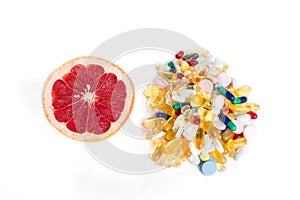 Grapefruit and pills, vitamin supplements on white background with copy space, healthy diet concept