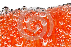 Grapefruit slice peeled pulpy capsules in water with air bubbles, in background light, close-up isolated, white, background,