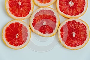 Grapefruit slices on the white background. Top view. Minimal colourful trend style. Copy space. Cut juicy slices. Tropical fruit