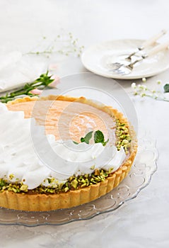 Grapefruit tart with whipped cream and pistachios on marble background