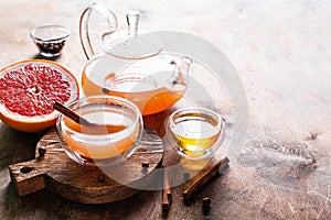 Grapefruit tea with spices and honey in a glass cup and teapot