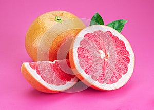 Grapefruits and grapefruit slices isolated on pink background