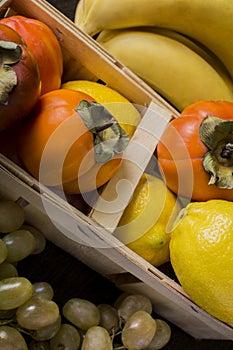 Grapes banana persimmons lemon in a basket