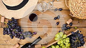 Grapes, bottle of wine, glass with wine, hat on a wooden background. View from above. Winemaking and harvesting concept
