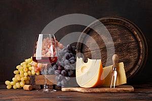 Grapes, chesse, glass of red wine and old barrel