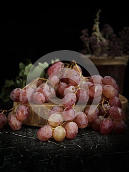 Grapes in a crystal vase, with a glass of wine on a black background.