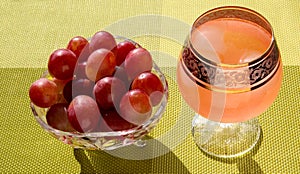 Grapes in a crystal vase with grape juice with ice on a bright green background