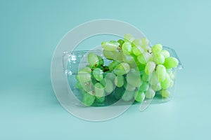 Grapes prepared for sale or delivery in a transparent plastic container on a green-blue background. Copy space