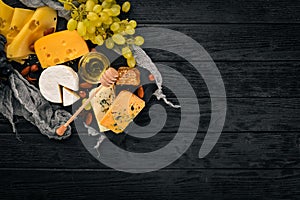 Grapes, red wine, cheeses, honey and nuts on a wooden background.