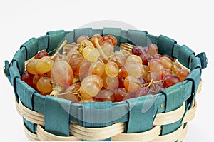 Grapes with small berries in a basket on a white background.