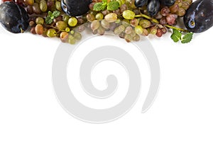 Grapes on white background. Ripe grape, plums and mint leaves at border of image with copy space for text. Top view. Various fresh