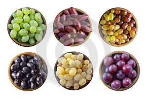 Grapes in a wooden bowl isolated on white background. Yellow, blue, pink and green grapes on white background.