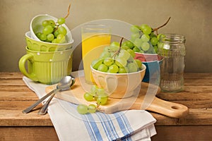 Grapes on wooden table. Still life composition with grapes and tableware.