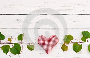 Grapevine border with red heart on white wooden table background