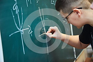 A graph of functions from mathematics is written by a student on a green school board.