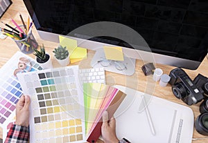 Graphic designer artist creative looking at colour chart at desk in office
