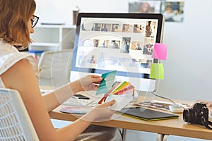 Graphic designer checks the color with color swatch at desk