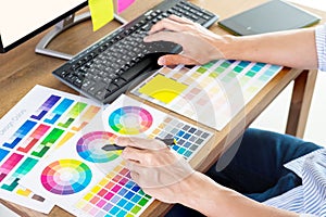 Graphic designer or creative holding Mouse and do his work material color pantone swatch samples art tools at desk in office
