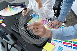 Graphic designer or creative working together coloring using graphics tablet and a stylus at desk with colleague