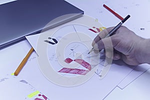 Graphic designer designs a logo against a background of sketches and drawings on a table. Printed logos on paper in a studio with