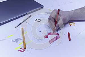 Graphic designer designs a logo against a background of sketches and drawings on a table. Printed logos on paper in a studio with