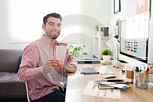 Graphic designer holding a color palette at his office desk