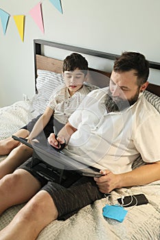 Graphic designer man remote working at home, his son sitting near him