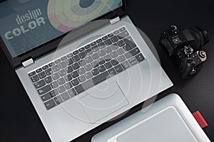 Graphic designer`s desk table, laptop, camera and graphic tablet on a dark wooden table. Concept graphic design studio