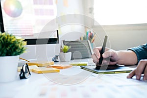 Graphic designer using graphics tablet to do work at desk.