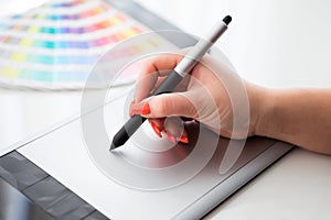 Graphic designer working on a digital tablet and with palette