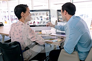 Graphic designers discussing over computer at desk in a modern office