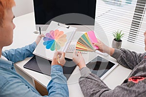 Graphic designers discussing over computer in modern office.