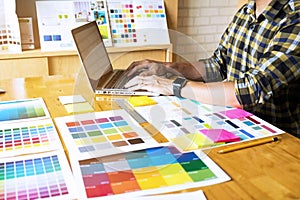 Graphic designers use the laptop to choose colors from the color bar example for design ideas, Creative designs of graphic design