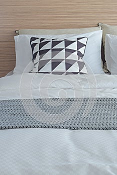 Graphic pattern pillow in black and white setting on bed with wooden laminated headboard