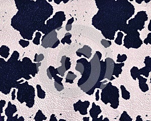 Graphic print on the skin of a cow on a dense, mass-produced upholstery fabric. Black spots on a beige background. Abstract