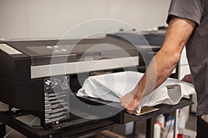 Graphic print technician work on digital t-shirt printing machine printer