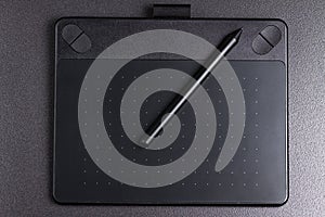 Graphic tablet with pen on black background top view.