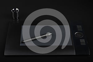 Graphic tablet and pen and stand for nibs on black background