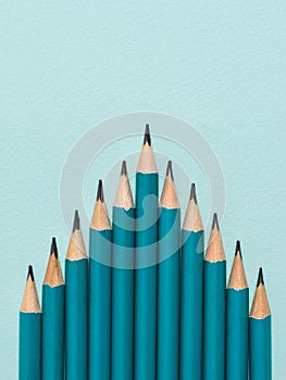 Graphite pencils on a blue background laid in the form of a pyramid.