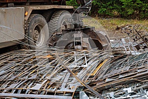 A grapple truck loads scrap industrial metal for recycling.