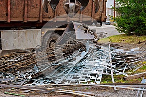A grapple truck loads scrap industrial metal for recycling