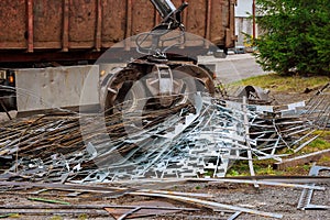 A grapple truck loads scrap industrial metal for recycling.