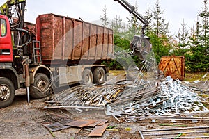 A grapple truck loads scrap industrial metal for recycling