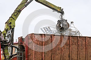 A grapple truck loads scrap industrial metal for recycling