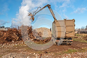 A grapple truck loads scrap industrial metal for recycling.