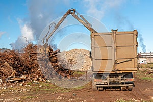 A grapple truck loads scrap industrial metal for recycling.