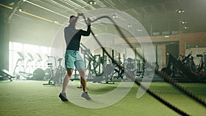 Grappler toss exercise on battle rope done by athletic young man in gym