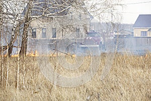 Grass is burning in meadow near private residential building. Ecological catastrophy. Destruction for ozone layer photo